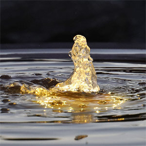 Sprudelrohr in Cortenstahl Wasserschale mit warm weißer Fontänen- und Schalenbeleuchtung.