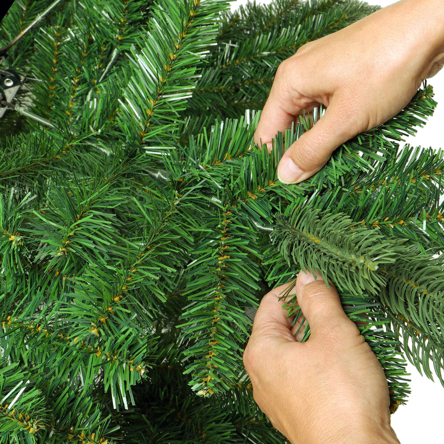 das Foto zeigt Hände, welche die Zweige des Künstlichen Weihnachtsbaums ausrichten und in Form zupfen